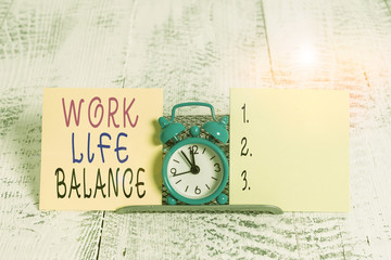 Writing note showing Work Life Balance. Business concept for Division of time between working or family and leisure Mini blue alarm clock standing above buffer wire between two paper