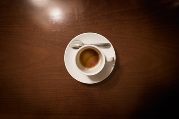 Empty cup. Empty coffee white cup on top of a wooden table in a hotel.