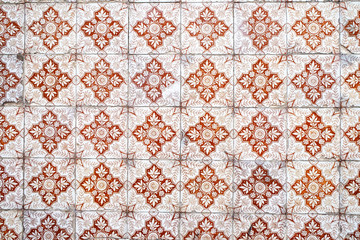 Wall with traditional Portuguese decor tiles azulezhu red tones on a beige background.