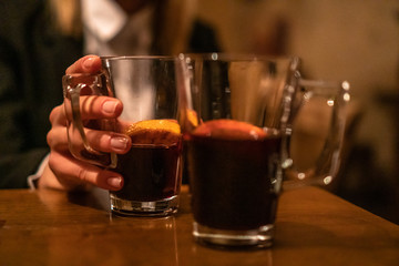 Beauty, elegant business woman with two glasses of mulled wine with orange and lemon inside the bar in basement. Wroclaw, Poland