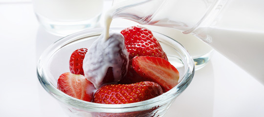 Cream flows on strawberry. White background. High key. Close up. Selective focus.