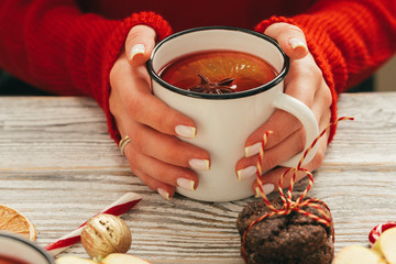 Cup of mulled wine in woman's hands on wooden table