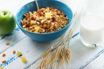 Health food. Muesli with milk and the baked apple on old wooden background. High key. Close up. Selective focus.