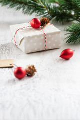 Christmas gift box decorated with red ball and natural cone on white cement background. Merry Christmas and Happy New Year concept