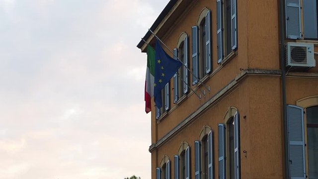 Italian flag and European Union Flag hanging against a building ; Milan, Italy