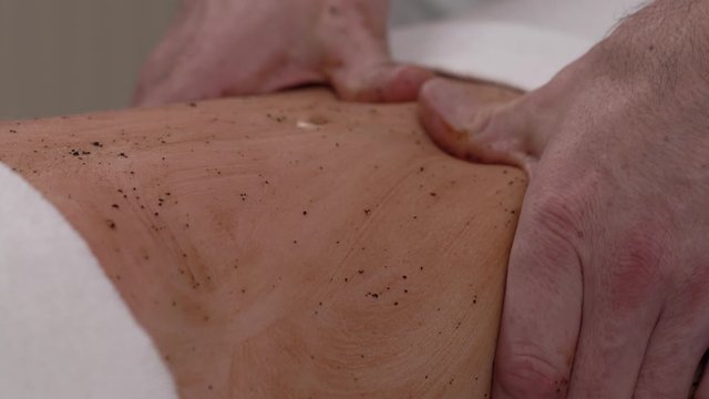 Masseur makes chocolate wrapping to his young female client. Close-up demonstration video