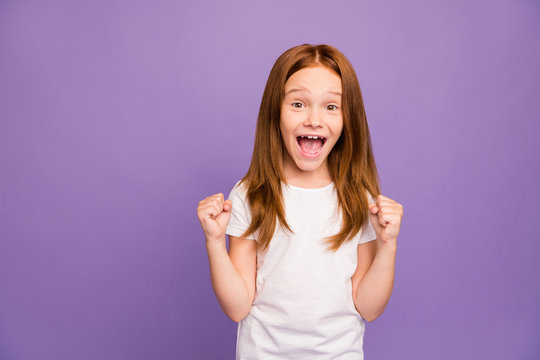 Photo of pretty excited little foxy lady raising fists cheering classmates at sports competition supporting screaming wear white t-shirt isolated purple background
