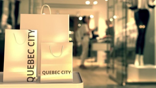 Paper shopping bags with QUEBEC CITY text against blurred store. Canadian shopping related clip