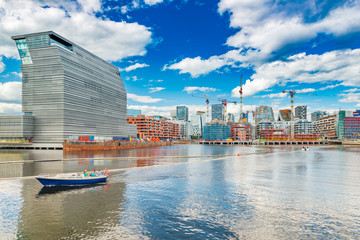 Cityscape of downtown Oslo with modern architecture, boat with a group of people and the blue sky with clouds, Norway