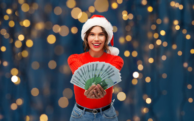 christmas, holidays and finance concept - happy smiling young woman in santa helper hat holding...
