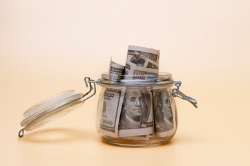 Dollar bills in glass jar on pastel background.money saving financial concept.