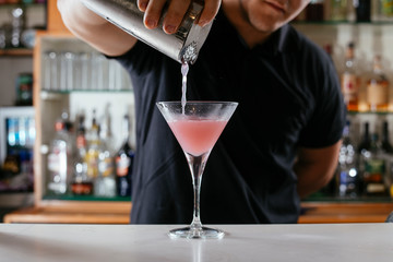Professional barman making cosmopolitan cocktail.