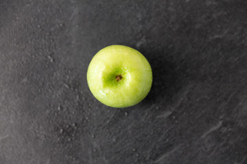 fruits, diet, eco food and objects concept - ripe green apple on slate stone background