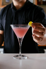 Professional barman making cosmopolitan cocktail.