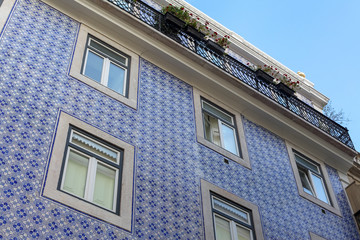 A beautiful architecture of the traditional tiled walled facade with large glass doors and windows and the iron balcony in the city of Lisbon in Portugal
