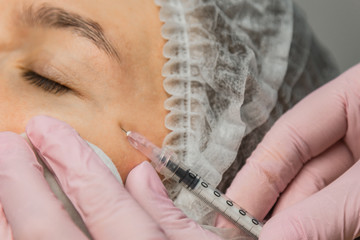 contour plastic. A cosmetologist injects a botulinum toxin to tighten and smooth out wrinkles on...