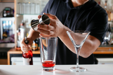 Barman making red cocktail. Professional bartender preparing Manhattan cocktail. 