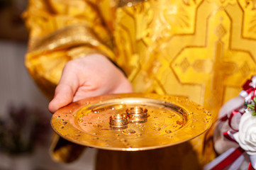 Gold wedding rings on the gold plate in the church