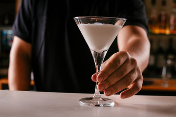 Close up of bartender serving martini. Cocktail based on milk and coffee.