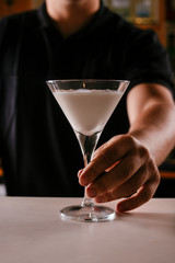 Close up of bartender serving martini. Cocktail based on milk and coffee.