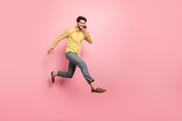 Fototapeta na wymiar Full body profile photo of handsome guy jump high hold telephone speaking with girlfriend rushing date wear striped shirt pants isolated pink color background
