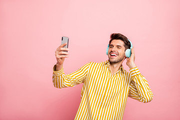 Photo of handsome guy holding telephone hands recording video with new earflaps new post with modern review wear hipster striped shirt isolated pink color background