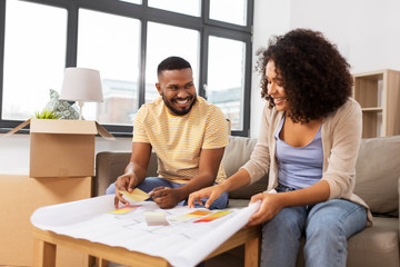 accommodation, moving and real estate concept - happy african american couple with blueprint and color palettes at new home