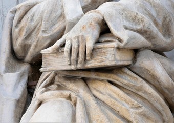 Statue of saint  holding holly book in the hands close detail