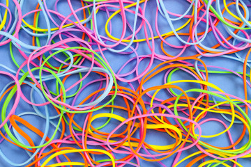 A pile of neon colored elastic rubber bands against a blue background