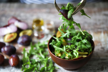 Selective focus. Healthy salad mix male hands with a spoon and fork. Arugula plum salad.