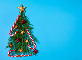 Obraz premium Christmas composition. The Christmas tree is made of juniper branches, gingerbread snowflakes, caramel canes and red gift bows on a light blue background. Christmas, winter, New year.
