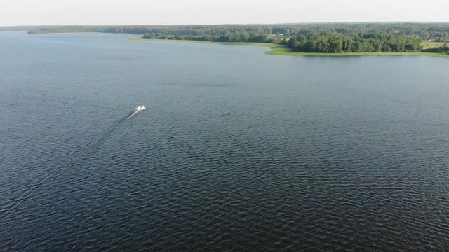 Motorboat at high speed moving to the shore in Sunny clear weather. Big deep lake with motorboat. The camera follows the motorboat
