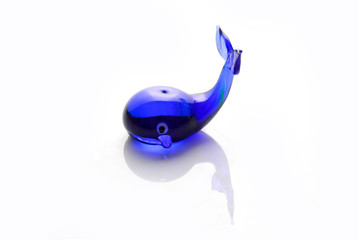 Wonderful figure of a blue whale made of glass photographed on the lumen.Isolated mini toy.Side view.
