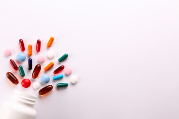 Flat lay composition with bunch of different colorful pills scattered from the bottle over the...