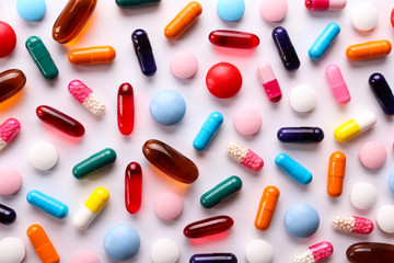 Fototapeta Flat lay composition with bunch of different colorful pills in scattered all over the table. Pile of opened medication on paper textured background. Close up, copy space. obraz