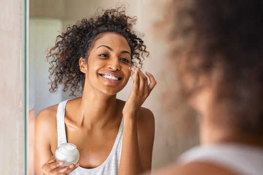 Black girl applying lotion on face
