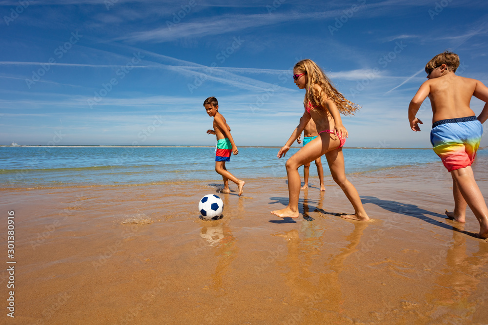 Wall mural group of kids play soccer on the sea sand beach