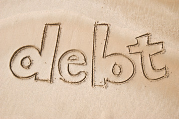 Debt message handwritten on smooth textured brown sand beach