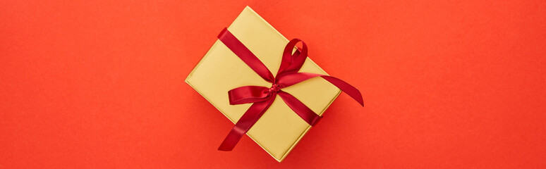 top view of golden gift box on red background, panoramic shot