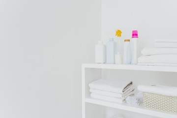 Stack of white soft towels with soft conditioner liquid. White background with copy space for your information. Cleanliness concept. Natural light