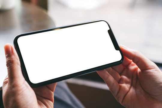 Mockup image of a woman holding a black mobile phone with blank white desktop screen