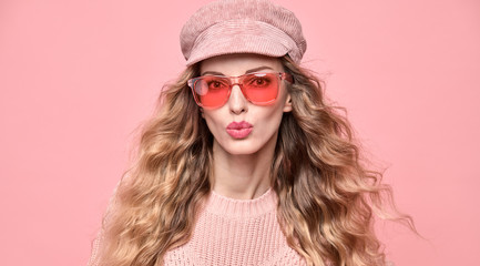 Fashion. Beautiful woman in pink jumper, trendy hairstyle, make up. Adorable funny blonde girl on pink. Cheerful fashionable young lady, wavy hair, makeup. Creative fun beauty pastel shot