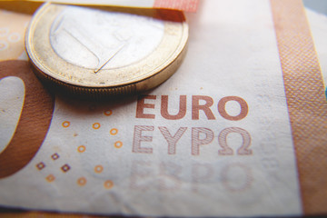 Macro photo of a coin in 1 Euro on a blurred background banknote in 50 euro. Money background. Extremely small depth of field.