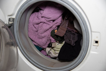 Overflowing clothes Washing machine broken down. Things that were washed in the washing machine are spoiled. Leaking white washing machine.