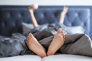 good morning concept - female hands and legs sticking out from the blanket