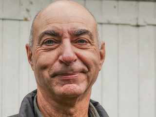 Mature man smirks skeptically and look at camera.