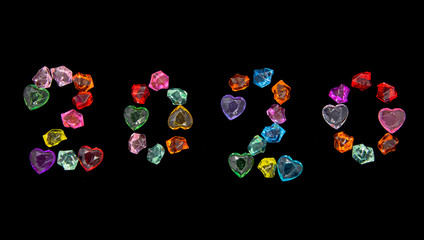 Bright glass ornaments and hearts are lined with 2020 figures on a black background.