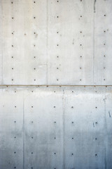 Fresh new concrete wall background with raw construction formwork lines and tie hole plugs