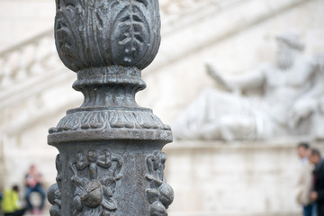 ornamental lamp post in front of statue on the facade of senators palace at capitoline hill