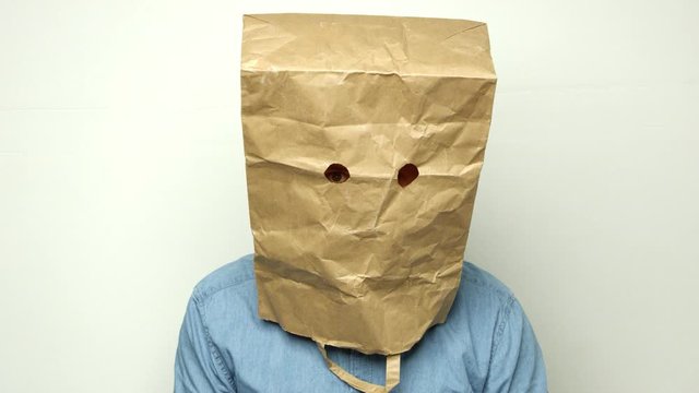 paranoid man has a bag on his head and looks into the camera. Shot on RED.